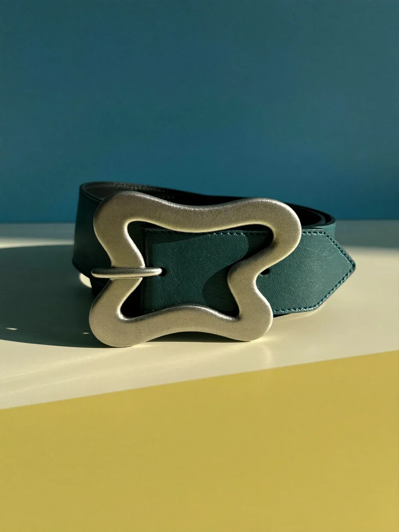 Studio illustrato di una cintura in pelle con fibbia astratta.